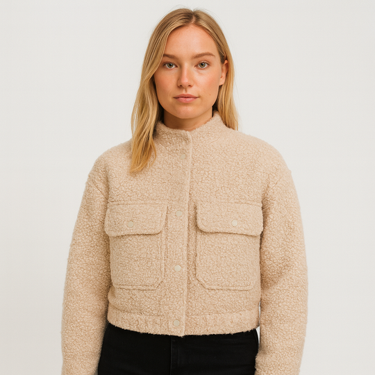 Beige bouclé cropped jacket with stand collar, snap button closure, long sleeves, and front flap pockets, displayed on a white background.