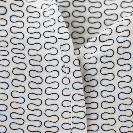 White button-down blouse with black geometric wave print and long sleeves.