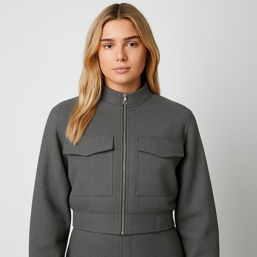 Cropped grey herringbone jacket with front zip closure, stand collar, and utility-style flap pockets.
